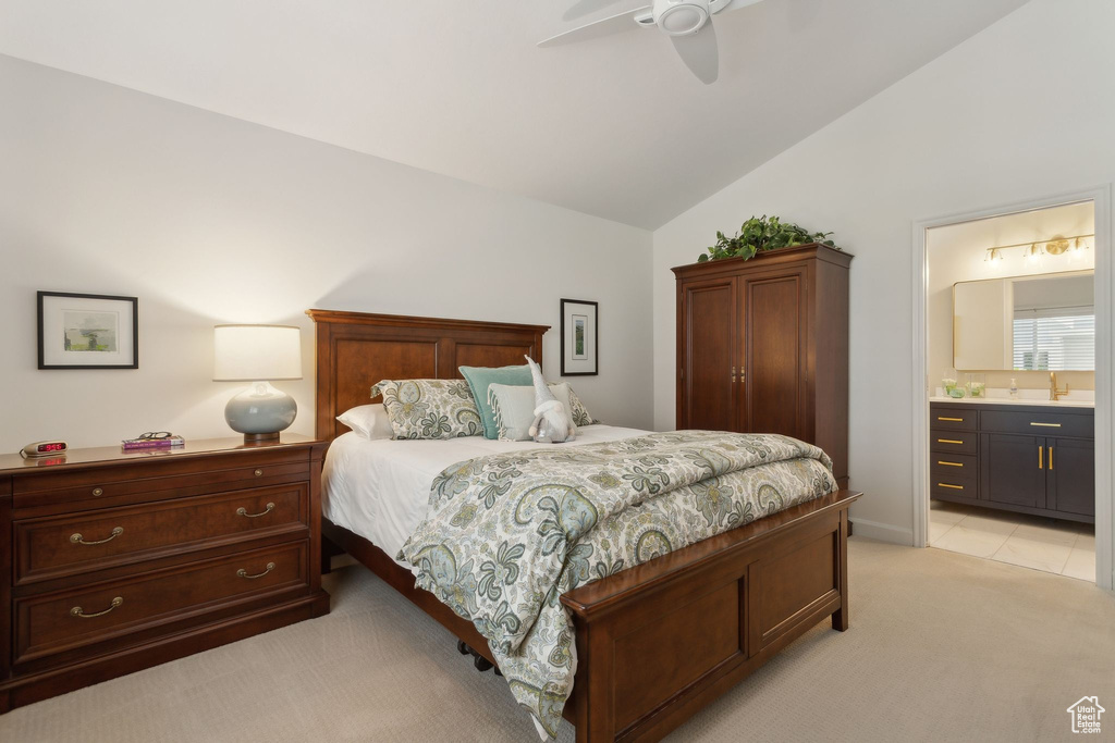 Bedroom featuring vaulted ceiling, light colored carpet, ensuite bath, a sink, and a ceiling fan