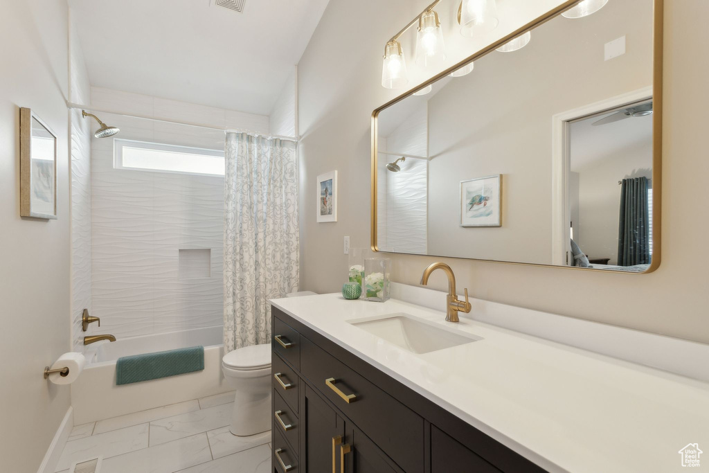 Full bath featuring marble look tiles, shower / bath combination with curtain, vanity, and toilet