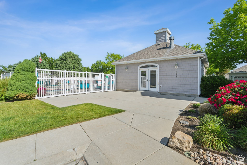 Back of house featuring french doors, roof with shingles, a patio area, and a chimney