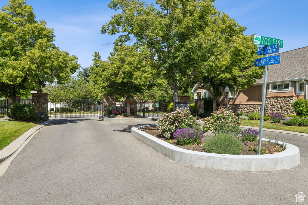 View of asphalt road with a gate, curbs, and a gated entry
