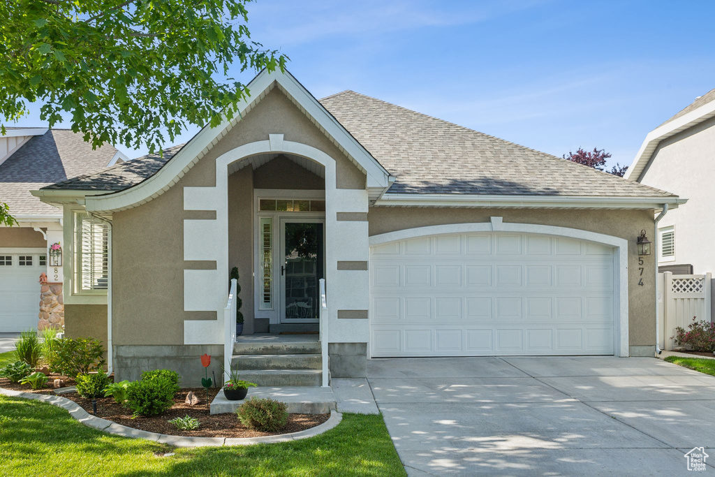 Ranch-style home with an attached garage, driveway, stucco siding, and roof with shingles