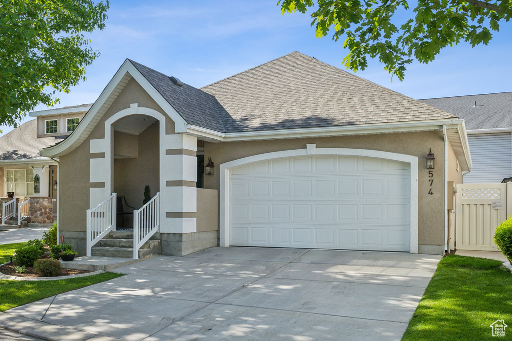 View of front of home featuring concrete driveway, an attached garage, stucco siding, and roof with shingles