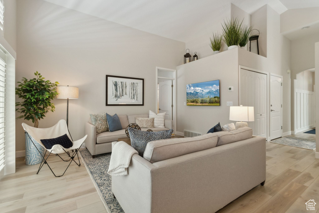 Living area featuring high vaulted ceiling, light wood-type flooring, baseboards, and arched walkways