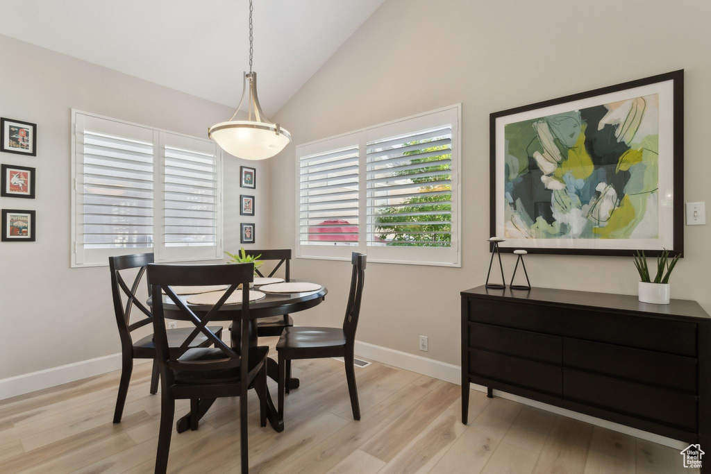 Dining room featuring light wood-style floors, lofted ceiling, and baseboards