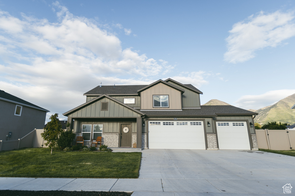Craftsman-style home with driveway, board and batten siding, an attached garage, and a shingled roof