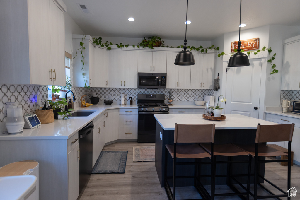 Kitchen with gas stove, stainless steel microwave, a sink, tasteful backsplash, and light countertops