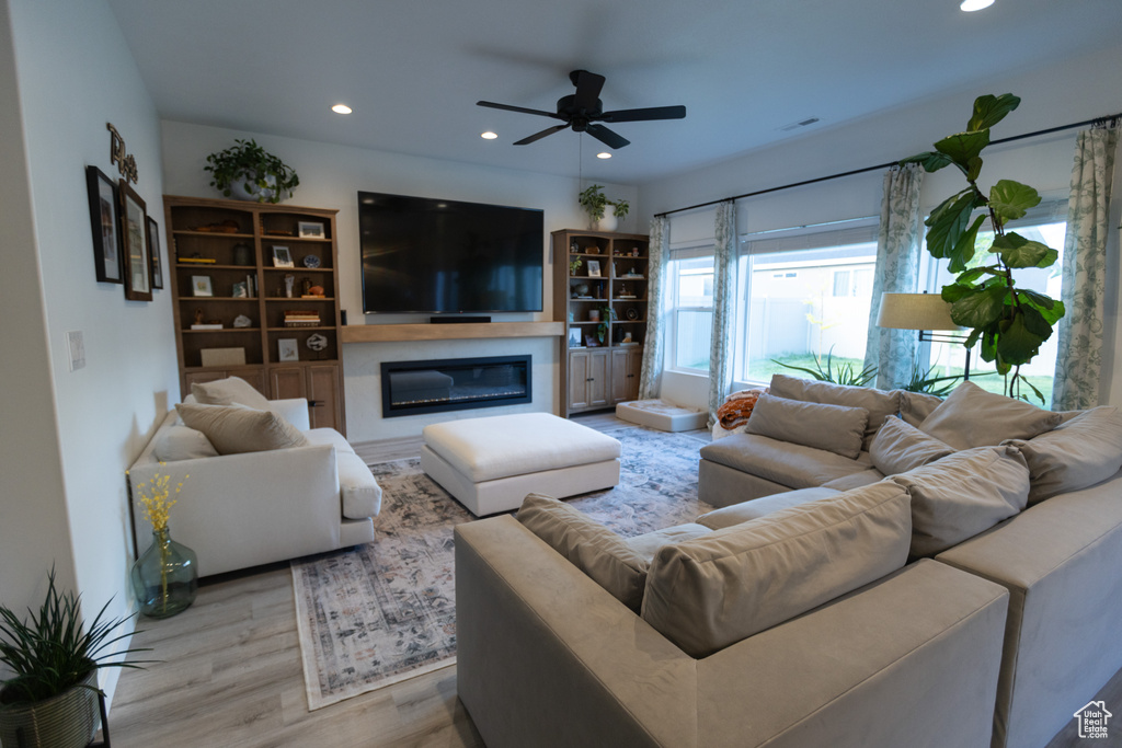 Living area featuring recessed lighting, wood finished floors, a ceiling fan, and a glass covered fireplace