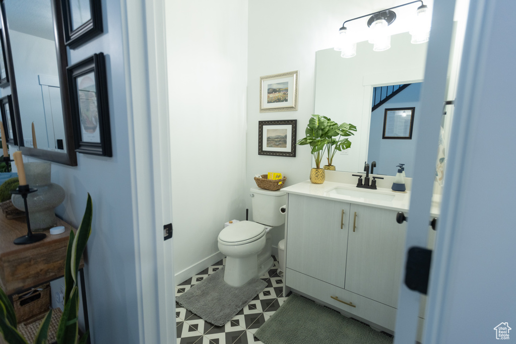 Half bath with toilet, vanity, and tile patterned flooring