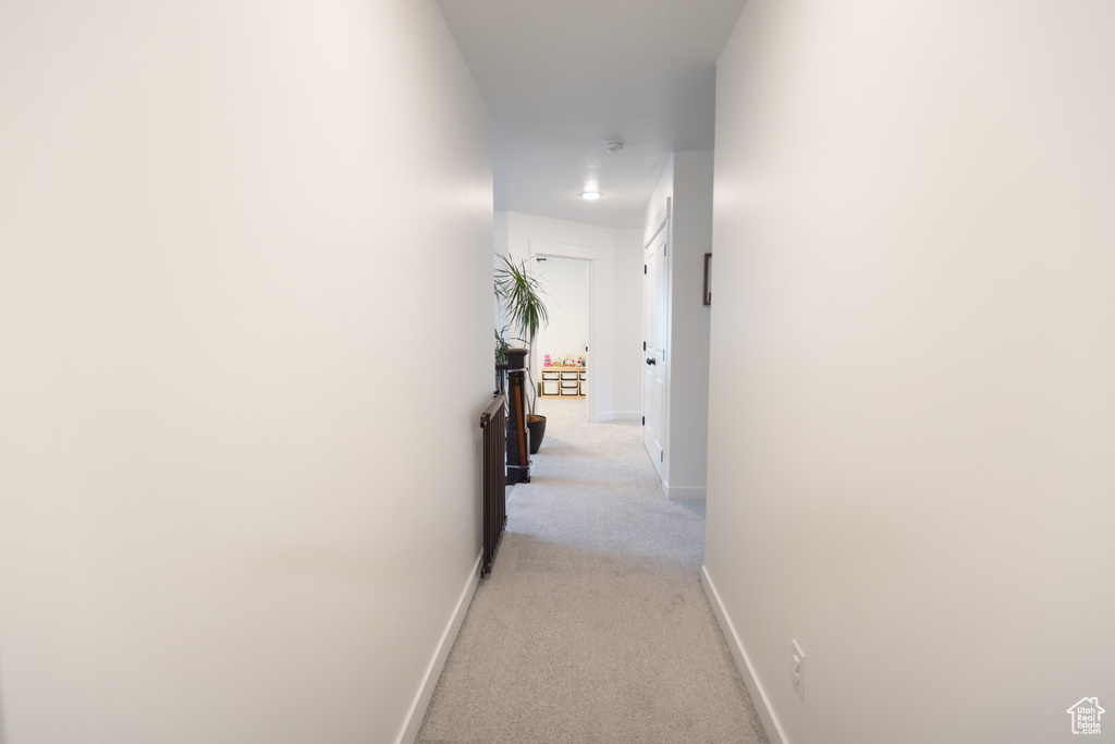 Corridor with light colored carpet and baseboards