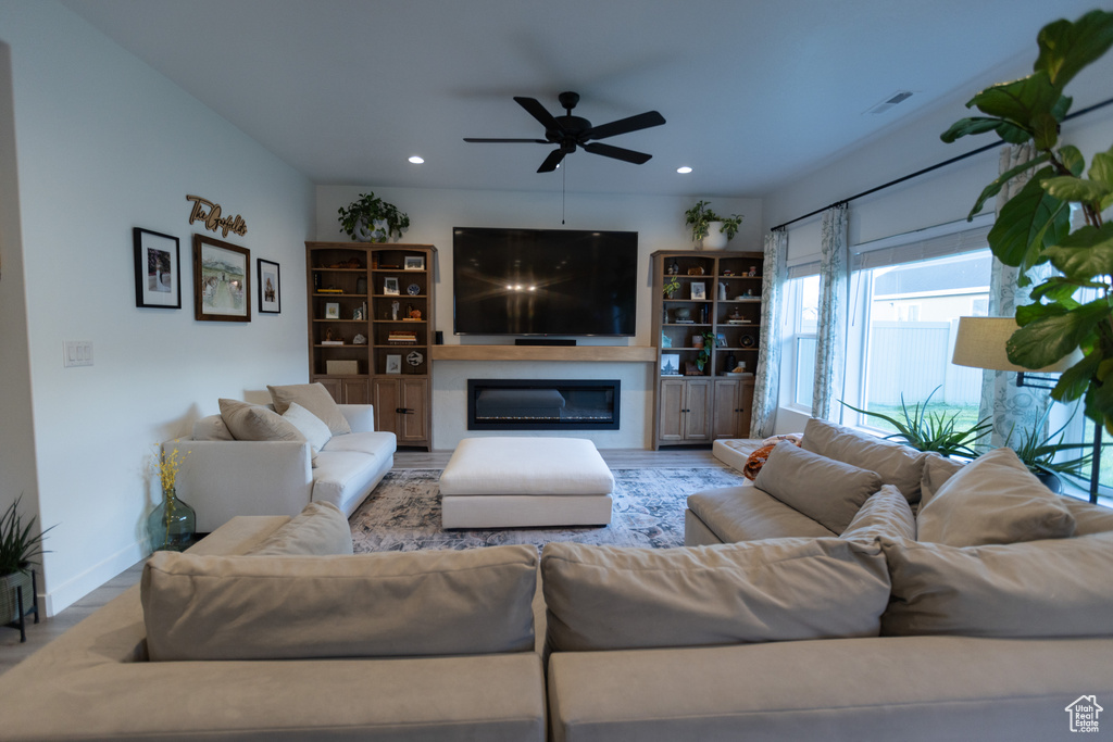 Living area featuring a glass covered fireplace, a ceiling fan, recessed lighting, and baseboards