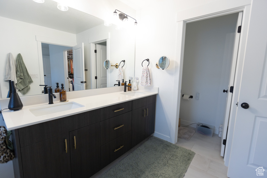 Bathroom featuring double vanity and a walk in closet