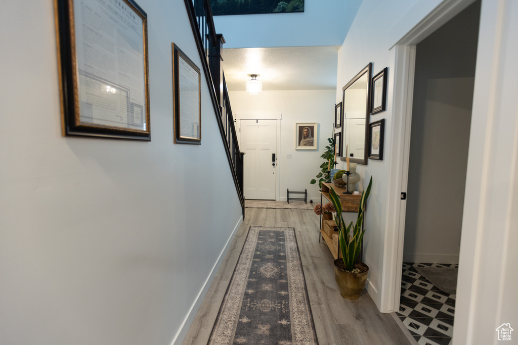 Corridor featuring light wood-style flooring, stairs, and baseboards
