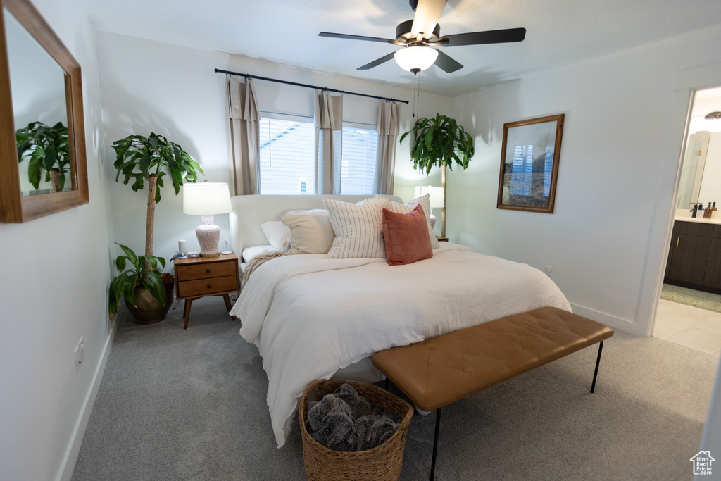 Bedroom featuring light colored carpet, baseboards, ensuite bath, and a ceiling fan