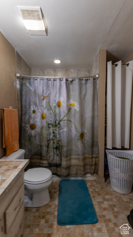 Bathroom featuring toilet, vanity, and a shower with shower curtain