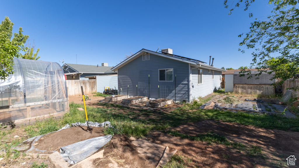 Back of house with an exterior structure, a vegetable garden, an outdoor structure, and a chimney