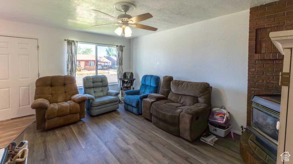 Living area featuring wood finished floors, a ceiling fan, and a textured ceiling