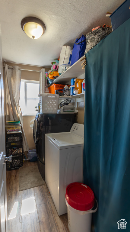 Laundry room featuring washer and clothes dryer and light wood-type flooring