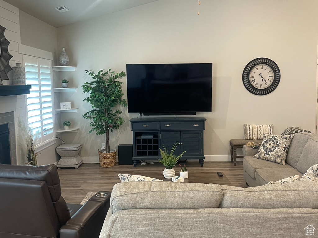 Living area featuring vaulted ceiling, ceiling fan, a glass covered fireplace, and wood finished floors