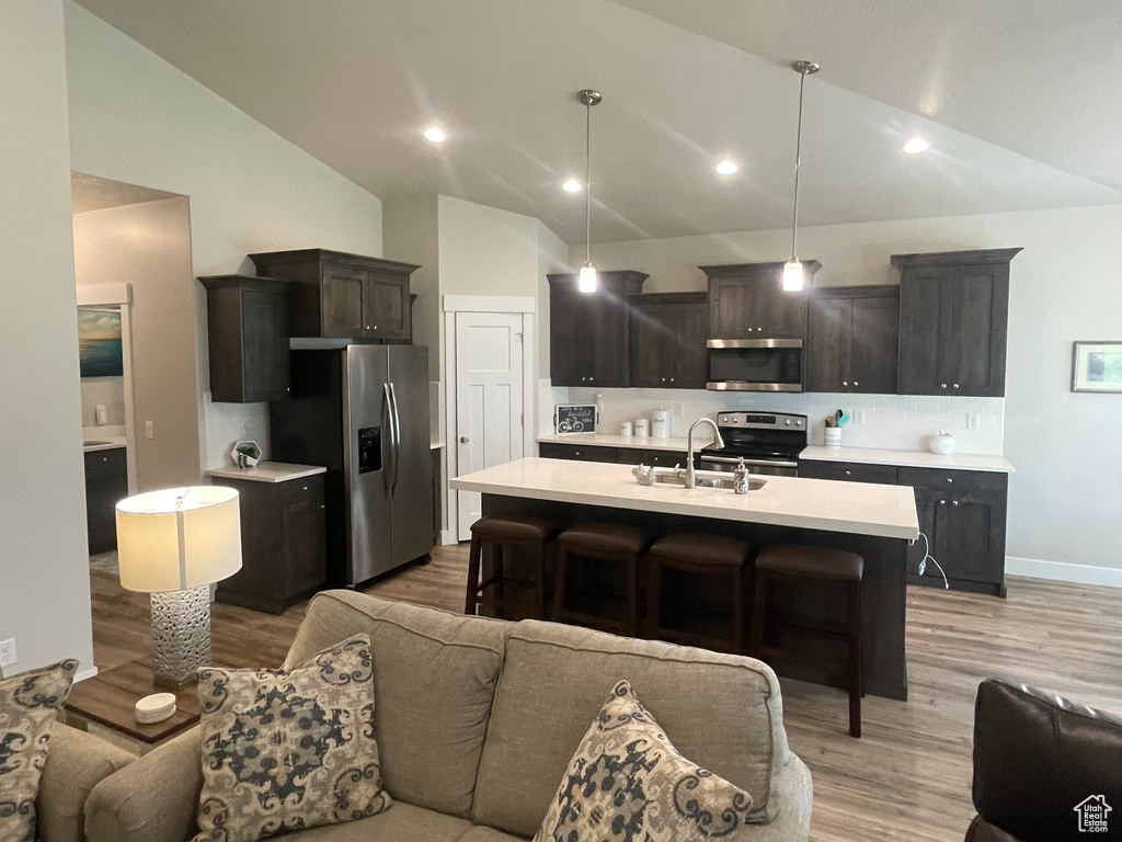 Living room featuring lofted ceiling, light wood-style floors, recessed lighting, and baseboards