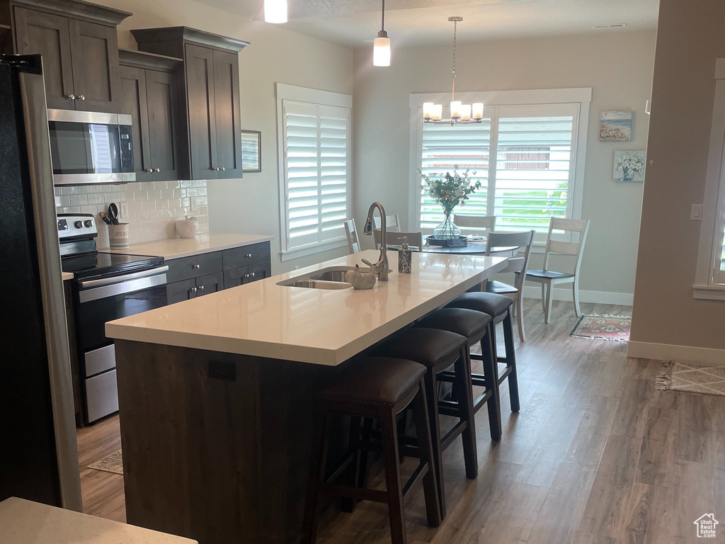 Kitchen featuring stainless steel appliances, light countertops, wood finished floors, a sink, and recessed lighting