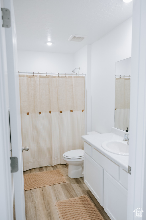 Full bath featuring wood finished floors, vanity, and toilet