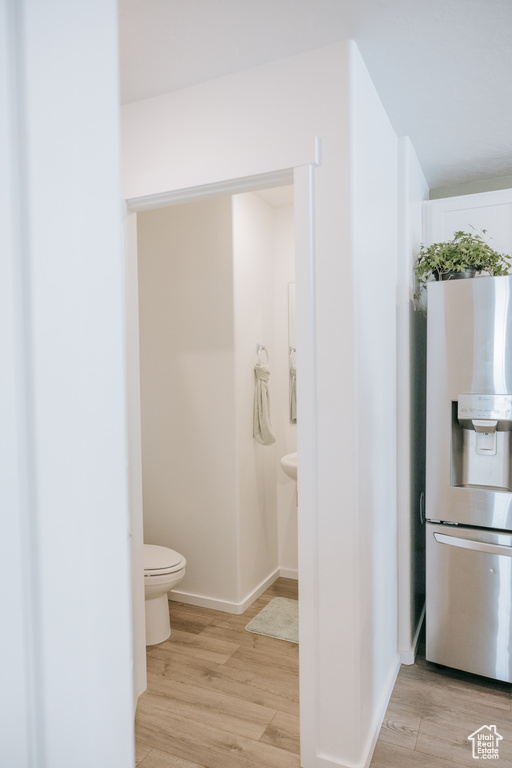 Bathroom with toilet, wood finished floors, and baseboards