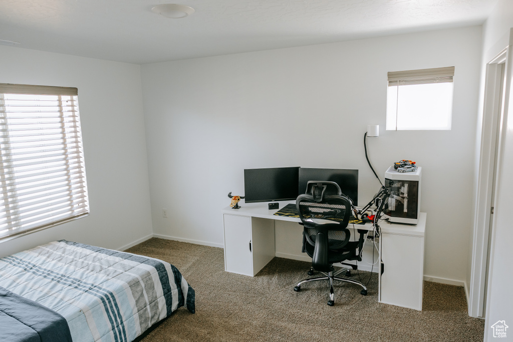 Carpeted bedroom with baseboards and a desk