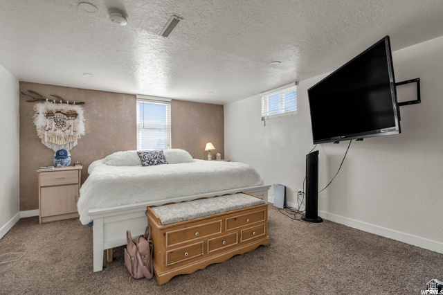 Carpeted bedroom with a textured ceiling and baseboards