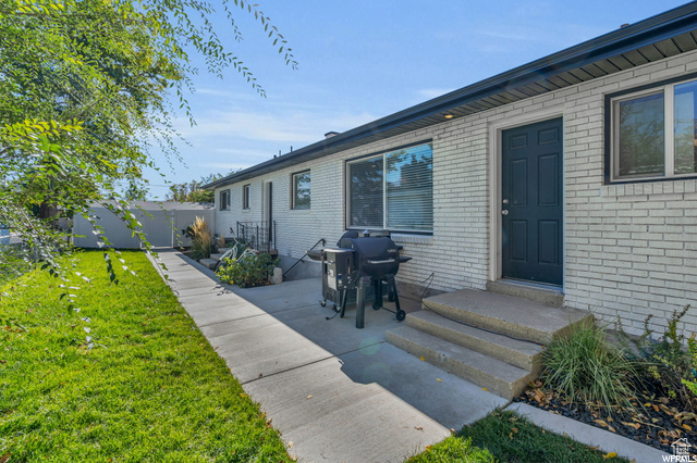 View of exterior entry with brick siding and a patio