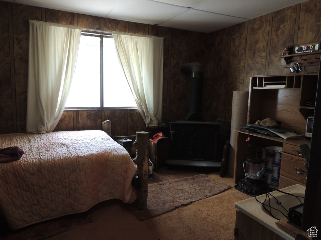 Carpeted bedroom featuring a wood stove and wood walls
