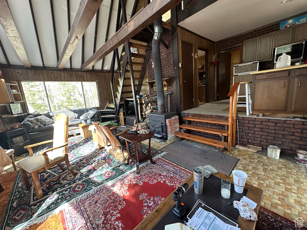 Living area with stairway, wooden walls, a wood stove, and beamed ceiling
