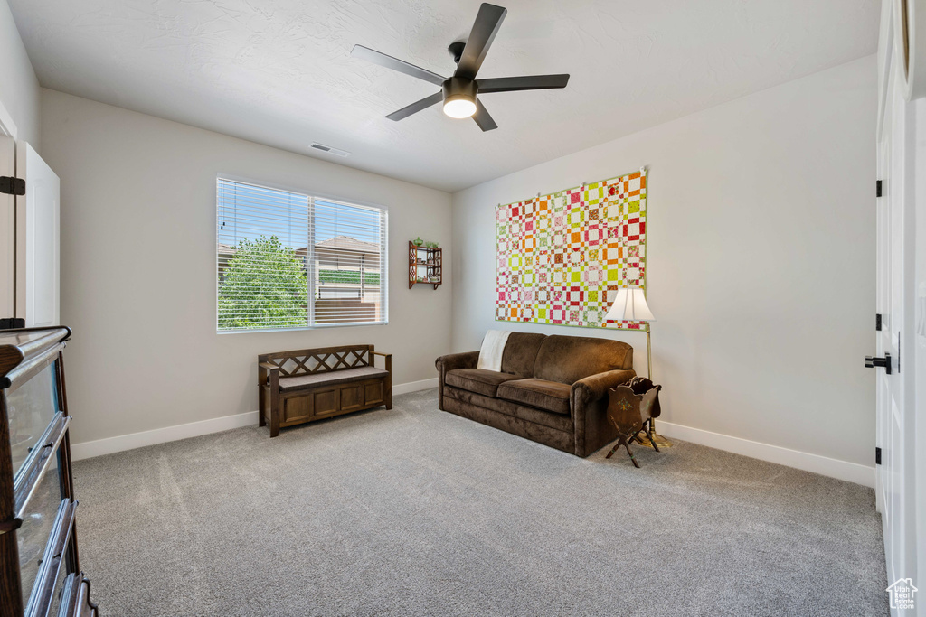Living area with ceiling fan, baseboards, and carpet floors