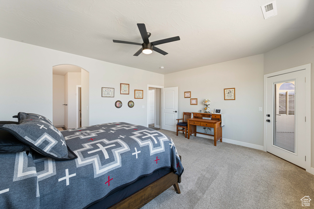 Carpeted bedroom with arched walkways and ceiling fan