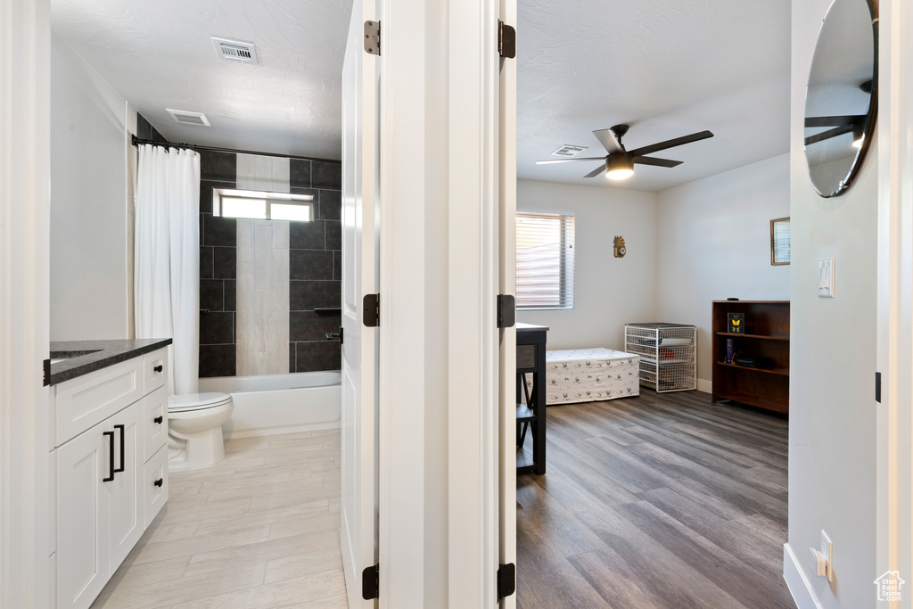 Full bathroom with a ceiling fan, vanity, toilet, shower / bath combination with curtain, and ensuite bath