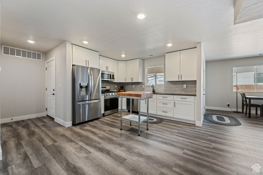 Kitchen featuring appliances with stainless steel finishes, baseboards, dark wood-type flooring, recessed lighting, and backsplash