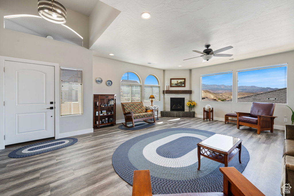 Living area featuring wood finished floors, baseboards, ceiling fan, recessed lighting, and a fireplace