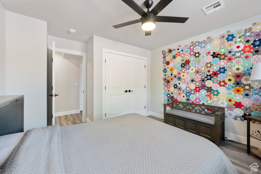 Bedroom with wood finished floors, baseboards, and a closet