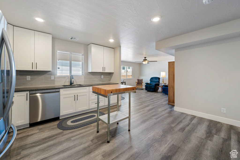 Kitchen with stainless steel appliances, a sink, wood finished floors, decorative backsplash, and recessed lighting