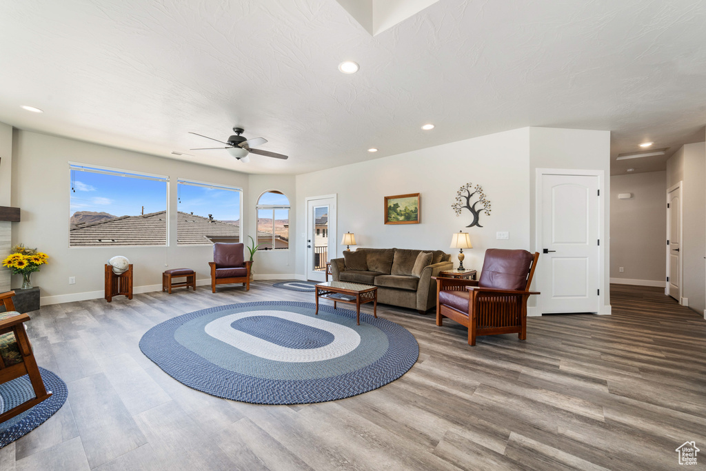 Living room with wood finished floors, baseboards, a ceiling fan, and recessed lighting