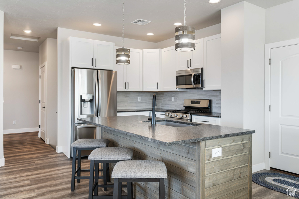 Kitchen featuring appliances with stainless steel finishes, dark countertops, baseboards, dark wood finished floors, and recessed lighting