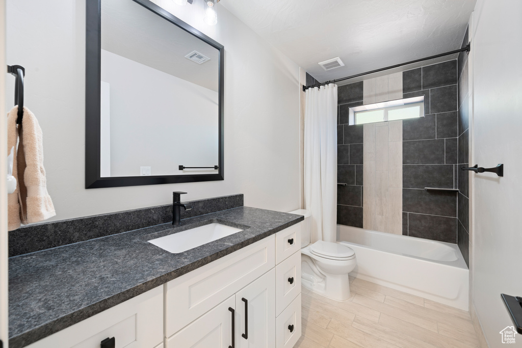 Bathroom featuring vanity, toilet, and shower / bath combination with curtain