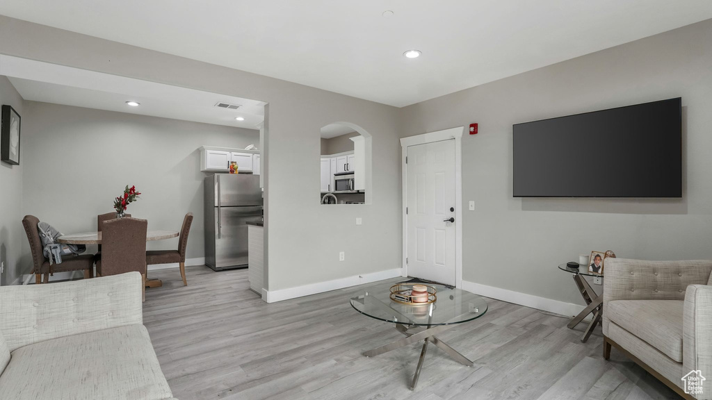 Living room featuring light wood finished floors, arched walkways, baseboards, and recessed lighting