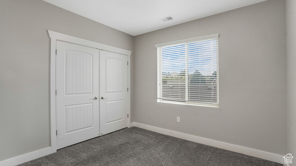 Unfurnished bedroom featuring dark carpet, baseboards, and a closet