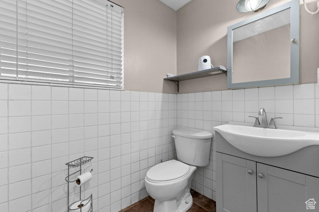 Bathroom with toilet, vanity, tile walls, and tile patterned flooring