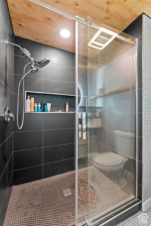 Full bath featuring a stall shower, toilet, and tile patterned floors