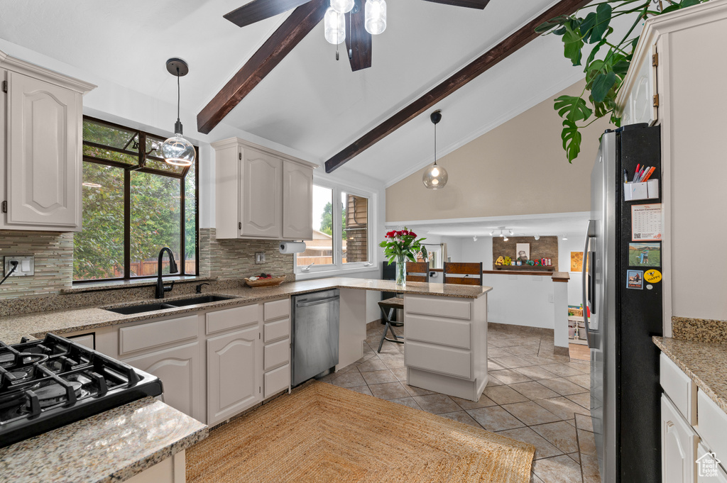 Kitchen featuring appliances with stainless steel finishes, a sink, tasteful backsplash, beam ceiling, and decorative light fixtures