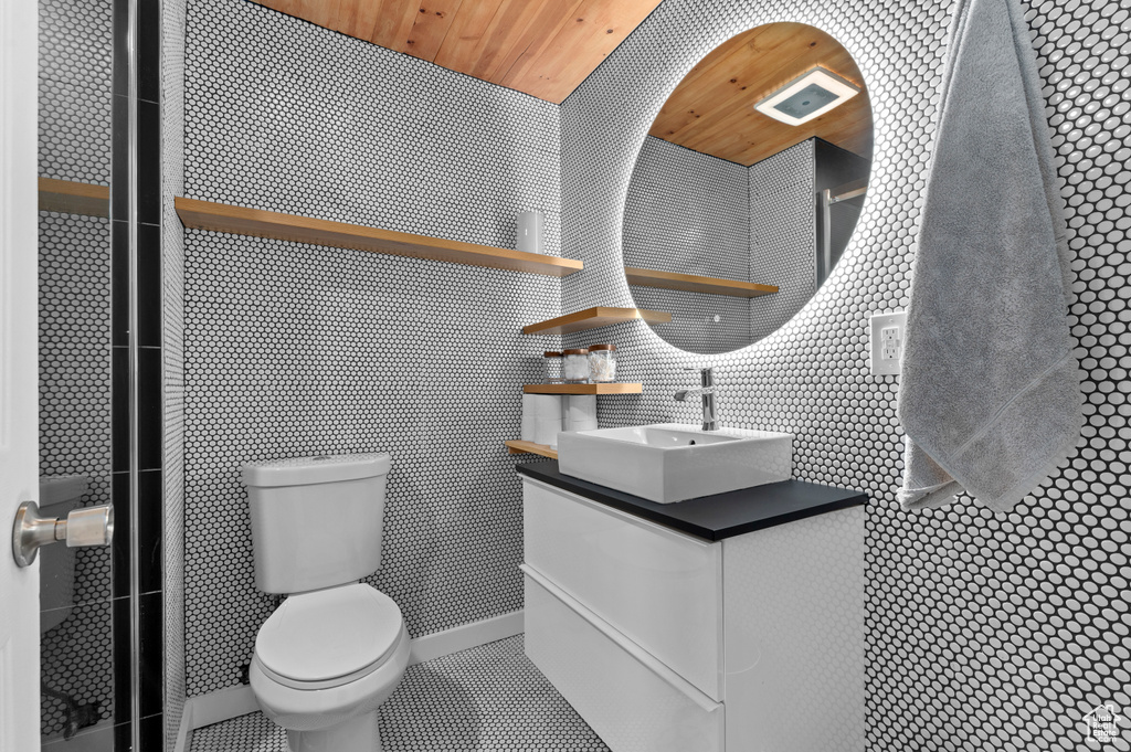 Bathroom with vanity, toilet, tile walls, wood ceiling, and tile patterned flooring