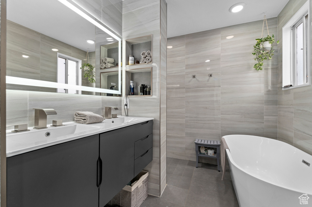 Full bathroom with tile walls, a wood stove, double vanity, a freestanding bath, and tile patterned floors
