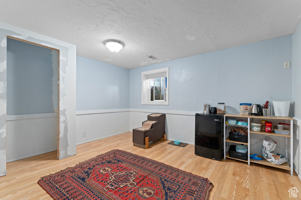 Sitting room with wood finished floors, a wainscoted wall, and a textured ceiling