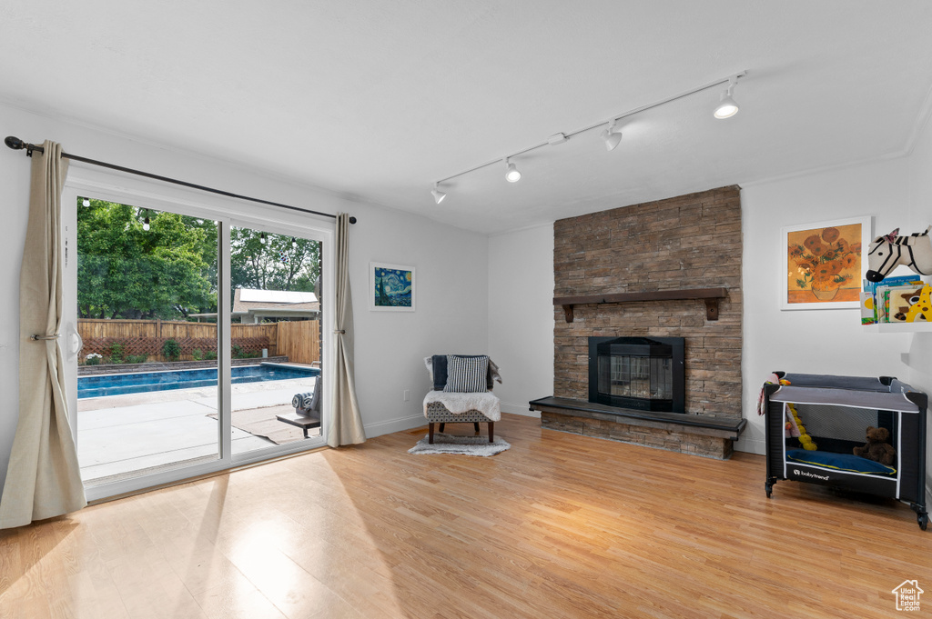 Unfurnished living room with track lighting, light wood-type flooring, a stone fireplace, and baseboards